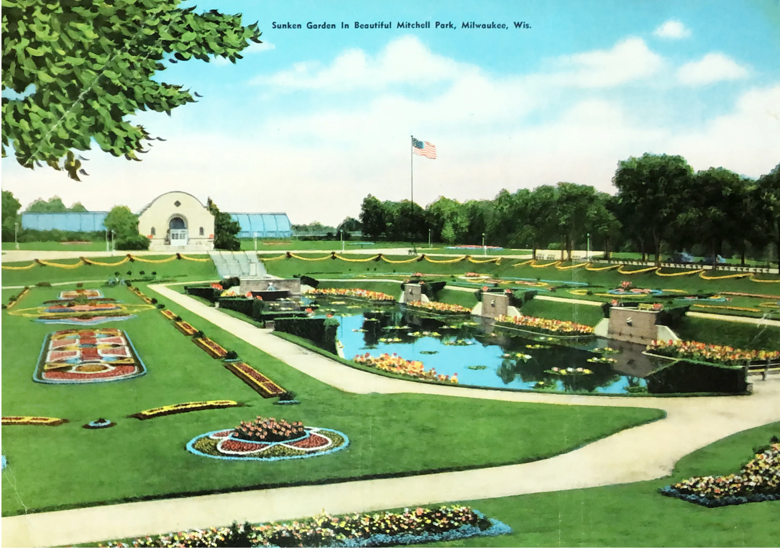 a sunken lily pond is surrounded by colorful flower beds. the conservatory is the background